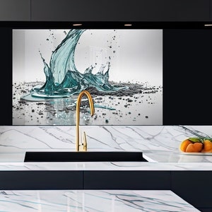 May include: A gold tap with a black sink in a modern kitchen with a white marble worktop. A glass splashback features a blue water splash design.