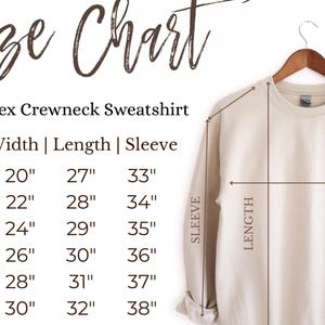 May include: A cream-colored unisex crewneck sweatshirt hanging on a wooden hanger. The image includes a size chart with measurements in inches for width, length, and sleeve for sizes S to 3XL. The text "Size Chart" is at the top.