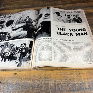 K&ouml;nnte beinhalten: Offene Magazinseiten mit Schwarz-Wei&szlig;-Fotografien und Text. Die &Uuml;berschrift lautet "THE YOUNG BLACK MAN". Bilder zeigen Menschen in verschiedenen Umgebungen, mit Text, der soziale Fragen diskutiert.