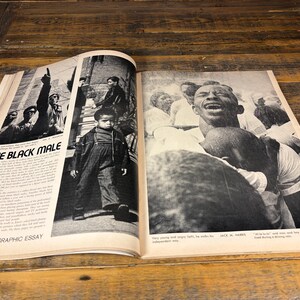 K&ouml;nnte beinhalten: Offenes Magazin mit Schwarz-Wei&szlig;-Fotografien. Die linke Seite zeigt den Titel "THE BLACK MALE" und ein Foto eines kleinen Jungen. Die rechte Seite zeigt eine Fotografie eines Mannes mit offenem Mund.