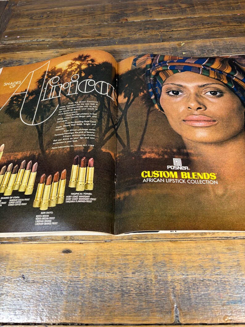 K&ouml;nnte beinhalten: Eine Doppelseite einer Zeitschrift mit einer Frau mit Kopftuch und einer Lippenstiftkollektion. Der Text lautet "Shades of Africa" und "Custom Blends African Lipstick Collection". Die Lippenstifte sind in goldenen Tuben mit verschiedenen Farbt&ouml;nen.