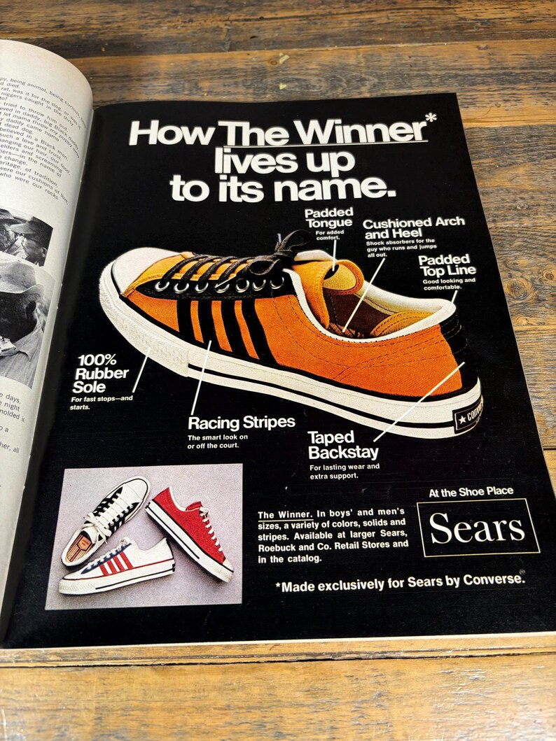K&ouml;nnte beinhalten: Werbung f&uuml;r Sears-Sneaker. Das Hauptbild zeigt einen orangefarbenen und schwarzen Sneaker mit wei&szlig;en Sohlen und Rennstreifen. Der Text hebt Merkmale wie die gepolsterte Zunge und das gepolsterte Fu&szlig;gew&ouml;lbe hervor. Zus&auml;tzliche Sneaker in Rot und Wei&szlig; sind ebenfalls abgebildet.