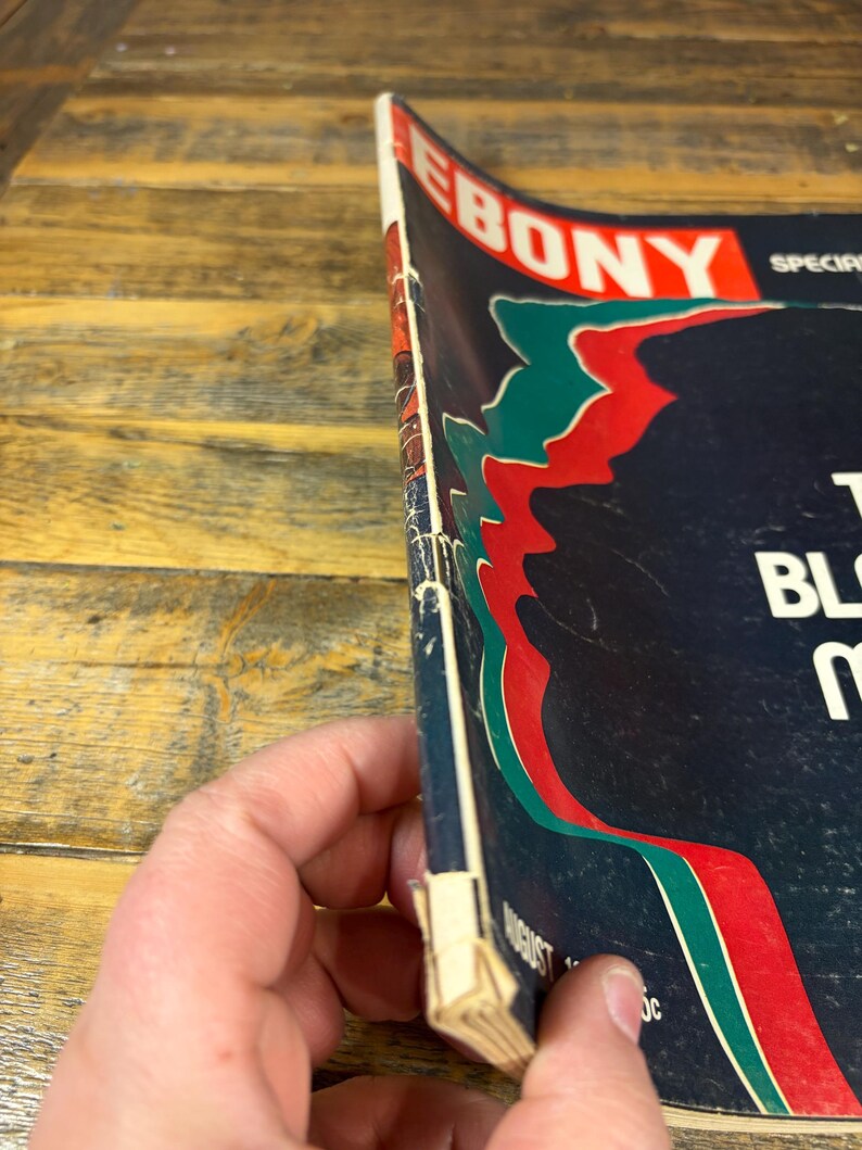 K&ouml;nnte beinhalten: Eine Vintage-Augustausgabe des Ebony-Magazins. Das Cover hat einen dunkelblauen Hintergrund mit roten, gr&uuml;nen und wei&szlig;en Akzenten. Der Titel des Magazins, "EBONY", ist in Rot und Wei&szlig; dargestellt.