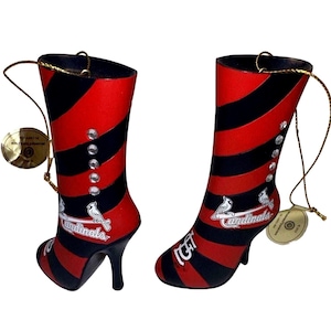 May include: Pair of decorative high-heeled boot ornaments. Each boot features alternating red and black stripes, embellished with clear rhinestones and a Cardinals logo. Includes a gold string for hanging.