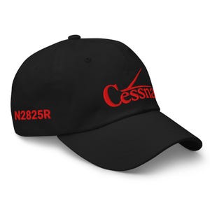 May include: Black baseball cap with the red embroidered word "Cessna" and the number "N2825R". The cap has a curved brim and a six-panel design. This hat is a great accessory for aviation enthusiasts.