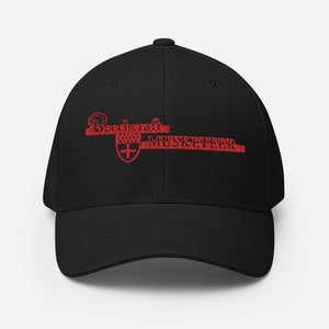 Könnte beinhalten: Schwarze Baseballkappe mit rotem gesticktem Text "Beechcraft MUSKETEER" mit einem roten Schild und Kreuz.