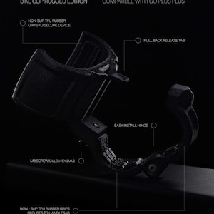 Infographic of the Bike Clip Rugged Edition, a Go plus + compatible handlebar mount, against a black background. Labels highlight key features: non-slip TPU rubber grips for both the device and handlebar, a pull-back release tab, and an easy install hinge with an M3 screw. The matte-black, carbon fiber infused 3D printed accessory is designed to securely hold a circular mobile gaming auto-catcher on bikes or scooters, offering a durable, hands-free mounting solution for active players.