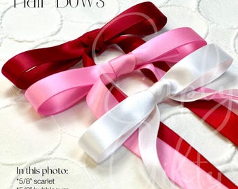 May include: Three hair bows in different colors: scarlet red, bubblegum pink, and white. Each bow is made of satin ribbon and tied in a classic bow shape. The bows are arranged on a white background.