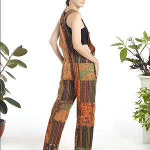May include: A woman wearing a patchwork jumpsuit with a variety of colors and patterns, including orange, brown, green, and blue. The jumpsuit has a wide leg and a relaxed fit.