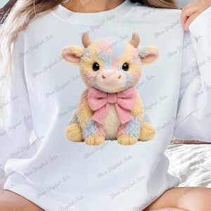 Può includere: Un peluche a forma di mucca dai colori pastello giallo, blu e rosa, ornato da un fiocco rosa. La mucca ha piccole corna e si trova su uno sfondo bianco.