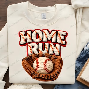 May include: Cream-colored sweatshirt featuring a baseball-themed design. The words "HOME RUN" are displayed in a bold, red-outlined font. Below the text is a baseball mitt holding a baseball. The design is a crochet style.