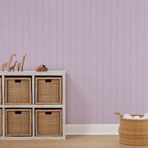 May include: A white shelf unit with six woven baskets, two wooden giraffe figurines, and a small wooden toy car. The shelf unit is against a light purple wall.