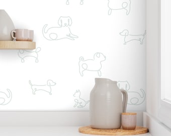May include: White wallpaper with a repeating pattern of light green line drawings of dogs. The wallpaper is in a kitchen setting with a white countertop and a wooden shelf with a pitcher and mugs.