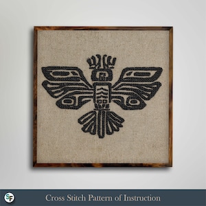 May include: A framed cross-stitch pattern featuring a black stylized eagle design on a tan linen background. The wooden frame surrounds the artwork, and the text "Cross Stitch Pattern of Instruction" is at the bottom.