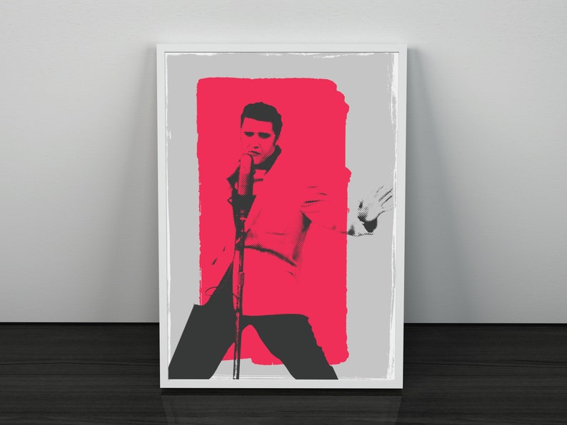 May include: A black and white image of a man singing into a microphone. The man is wearing a suit jacket and is standing in front of a red background.