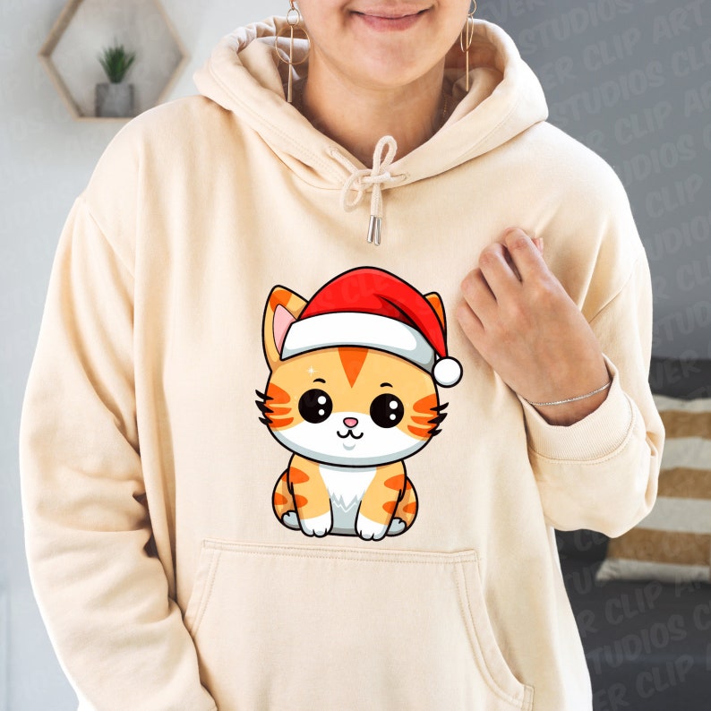 May include: A cream-colored hoodie with a cartoon image of a cat wearing a red Santa hat. The cat is orange and white with black stripes.