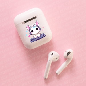 May include: White wireless earbuds with a charging case featuring a cartoon white cat wearing headphones and holding a record player. The cat has blue eyes and pink accents on its ears and headphones. The case has a pink background with small pink hearts.