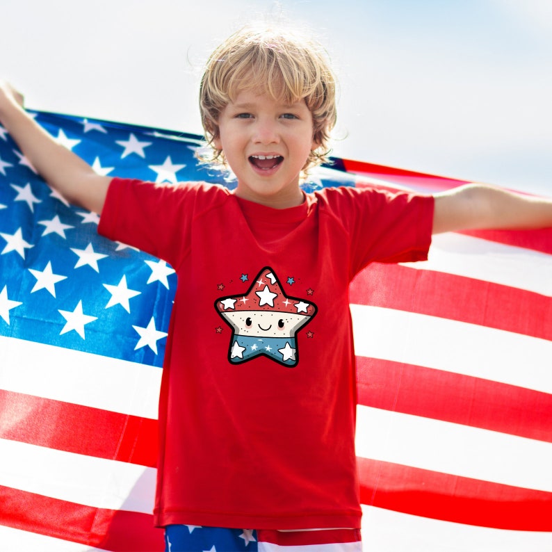 May include: A red t-shirt with a cartoon star design. The star is red, white, and blue and has a smiling face. The child wearing the shirt is holding an American flag.