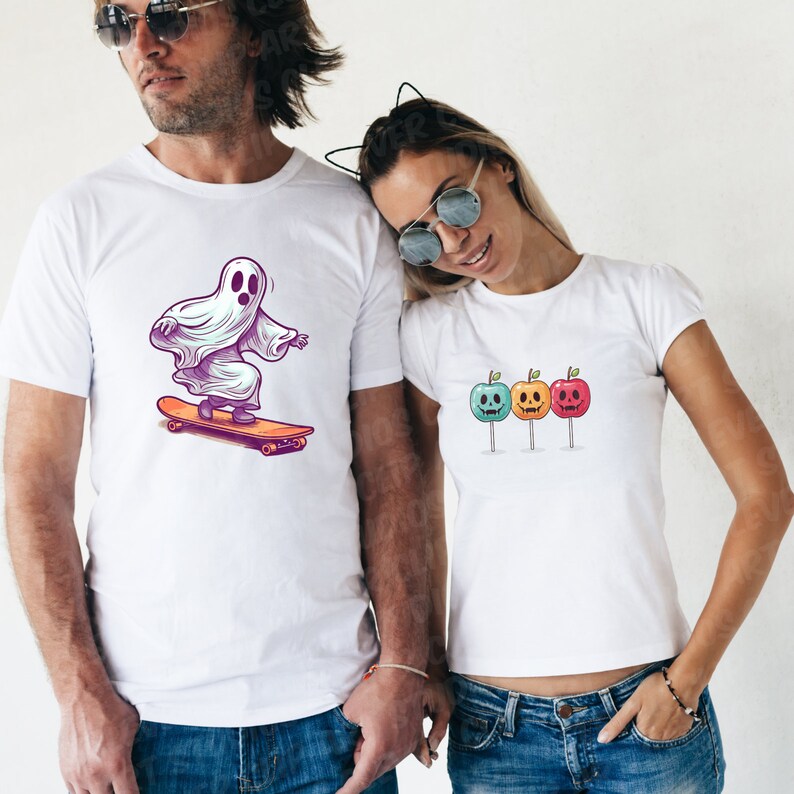 Puede incluir: Dos camisetas blancas con dise&ntilde;os de tem&aacute;tica de Halloween. Una camiseta presenta un fantasma haciendo skateboard, mientras que la otra camiseta tiene tres manzanas de caramelo con caras espeluznantes.
