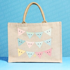 May include: A beige tote bag featuring a design of colourful bunting flags with smiling faces. The bunting is made of pink, blue, yellow, and green triangles with white polka dots.