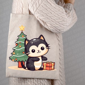 May include: A beige tote bag with a black cat holding a red gift box in front of a green Christmas tree with yellow ornaments and a yellow star on top.