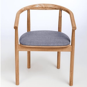 Può includere: Una sedia in legno con schienale curvo e un cuscino del sedile in tessuto grigio.