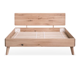 Può includere: Un telaio letto in legno con una testiera a doghe e una base a doghe. Il telaio del letto ha una finitura in legno chiaro ed è rialzato su quattro gambe.