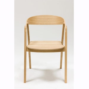 Könnte beinhalten: Ein heller Holzstuhl mit einer geschwungenen Rückenlehne und einem schlichten Design.