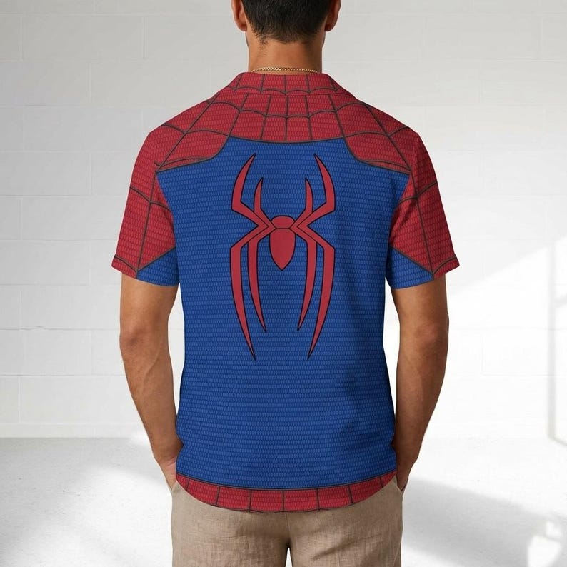 K&ouml;nnte beinhalten: Blaues und rotes Kurzarm-Shirt mit einem Spider-Man-Design. Das Shirt hat einen blauen K&ouml;rper mit einem roten Spinnenemblem auf dem R&uuml;cken und roten Schultern. Der Kragen und die &Auml;rmel sind rot mit einem Netzmuster.