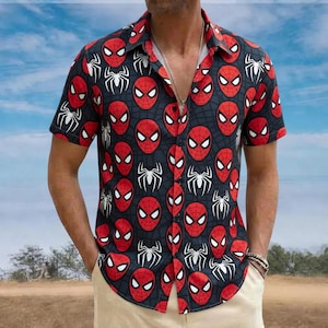 May include: Short-sleeved button-down shirt featuring a repeating pattern of red Spider-Man mask faces and white spider symbols on a dark blue background. The shirt has a classic collar and is made of a lightweight fabric.