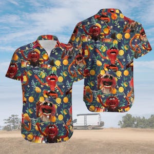 May include: A short-sleeve button-down shirt with a dark blue background featuring a repeating pattern of the red Muppet character Animal playing drums, interspersed with yellow citrus fruits, green leaves, and small white flowers.