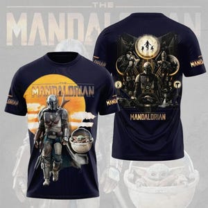 May include: Navy blue t-shirt featuring a graphic of The Mandalorian and Grogu against a sunset backdrop. The front of the shirt displays the Mandalorian in armor, while the back showcases a detailed scene with characters and the text "Mandalorian".