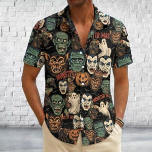 May include: A short-sleeve button-down shirt featuring a black background with a repeating pattern of colorful Halloween monsters, including ghosts, pumpkins, vampires, and zombies, with the text Monster Mas printed in a bold red font.