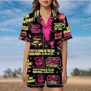 May include: Black pajama set with pink trim and various text graphics. The set includes a short-sleeved button-up shirt and matching shorts. The shirt features phrases like "This little piggy went to market" and "Today is gonna be the day".