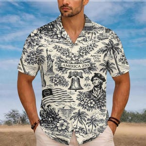 May include: Cream-coloured button-down shirt with a black and white toile pattern featuring American landmarks, palm trees, and floral elements. The shirt has the text "America 250" and "1776-2026".