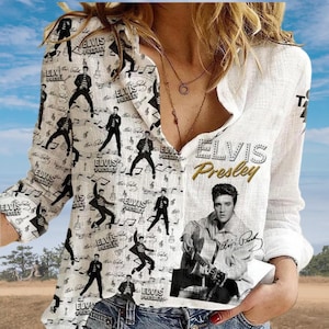 Può includere: Una camicia bianca a maniche lunghe con bottoni caratterizzata da un motivo grafico nero ripetuto di Elvis Presley in varie pose, note musicali e il testo "Elvis Presley" stampato in un carattere grande e audace sul lato destro.