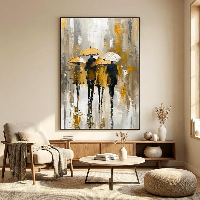 Contemporary umbrella wall art print showing romantic figures under umbrellas in a rainy city scene, styled in a warm neutral living room with natural decor.