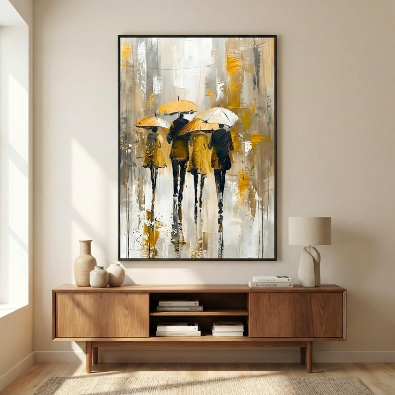 Abstract rain painting with yellow umbrellas and textured brush strokes, framed vertical wall art styled in a minimalist beige interior with wooden furniture.