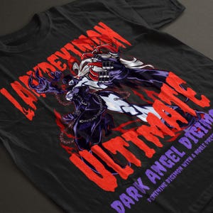 Può includere: T-shirt nero con grafica di un personaggio con accenti rossi, bianchi e viola. Il testo "LADYDEVIMON ULTIMATE" è in rosso e "DARK ANGEL DIGIMON" è in viola. La maglietta ha un girocollo.