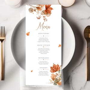 May include: A vertical rectangular menu card with a white background, featuring watercolor illustrations of orange and brown autumn leaves at the top and bottom. The text includes the word Menu followed by Appetizers, Main Course, Beverages, and Dessert.