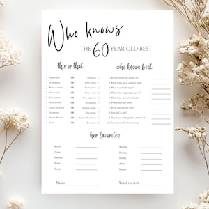 Op de afbeelding: Een wit papieren spelvel met de tekst "Who knows the 60 year old best". Het vel bevat invulvragen en "dit of dat" opties. Decoratieve droogbloemen staan op de achtergrond.
