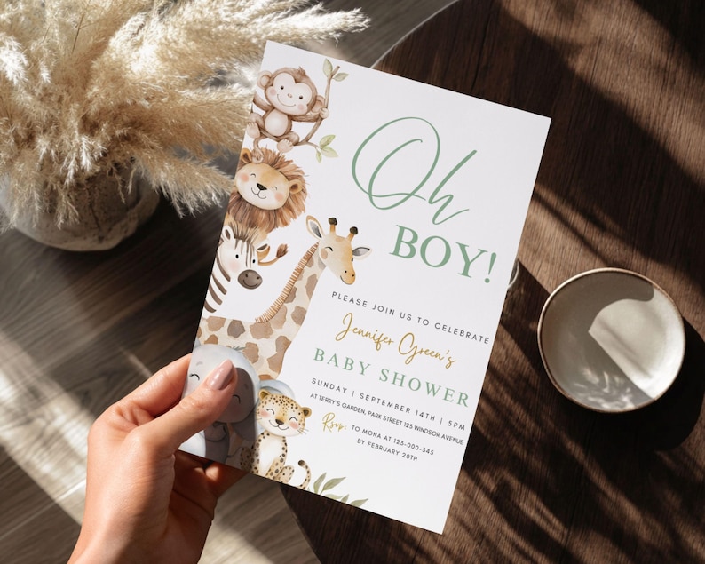Puede incluir: Una invitaci&oacute;n a un baby shower con el texto "Oh BOY!" en verde. La invitaci&oacute;n presenta ilustraciones de animales de safari, incluyendo un mono, un le&oacute;n, una cebra, una jirafa, un elefante y un leopardo. La invitaci&oacute;n es sostenida por una persona.