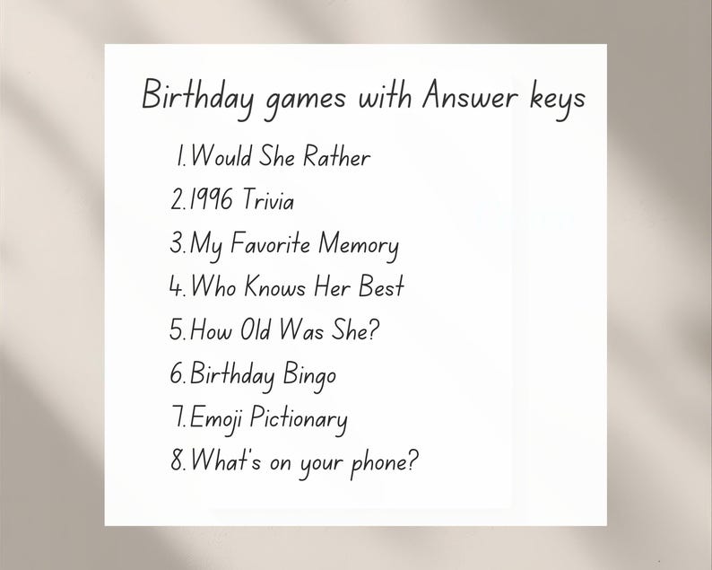 May include: A white card with black handwritten text listing birthday games with answer keys. Games include "Would She Rather," "1996 Trivia," "My Favorite Memory," "Who Knows Her Best," "How Old Was She?," "Birthday Bingo," "Emoji Pictionary," and "What's on your phone?"
