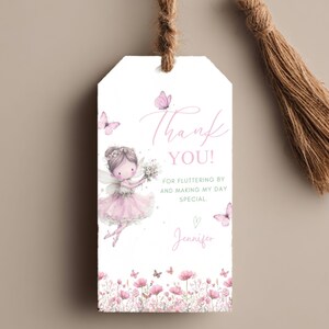 Op de afbeelding: Een witte cadeaulabel met een aquarel illustratie van een fee in een roze jurk, omringd door vlinders en bloemen. De label heeft de roze tekst "Thank You!" met extra tekst. Een bruine kwast hangt aan de bovenkant.