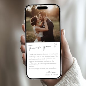 Op de afbeelding: Een smartphone toont een bedankkaart voor een bruiloft. De kaart heeft een foto van een kussend stel en een handgeschreven bericht: "Bedankt uit de grond van ons hart..." De kaart is ondertekend met "Emma & Philip."
