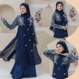 May include: A navy blue ensemble featuring a long-sleeved dress with floral embroidery and a flowing chiffon overlay. The outfit includes a matching head covering. The dress is adorned with delicate white floral accents.