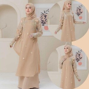 May include: A beige, long-sleeved dress with floral embroidery on the sleeves and bodice. The dress features a flowing, layered design and is paired with a matching headscarf. The overall style is modest and elegant.
