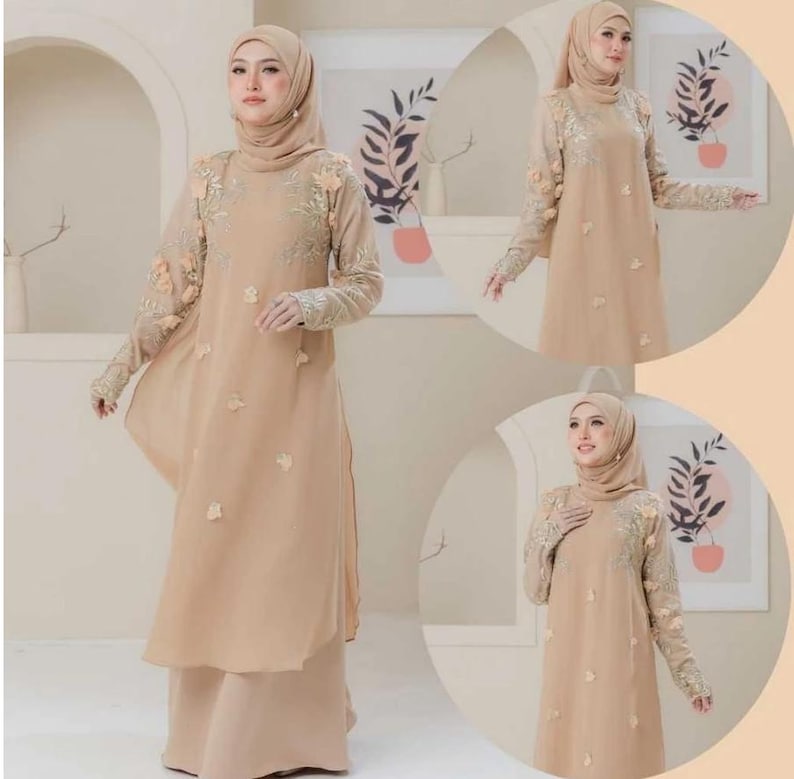 May include: A beige, long-sleeved dress with floral embroidery on the sleeves and bodice. The dress features a flowing, layered design and is paired with a matching headscarf. The overall style is modest and elegant.