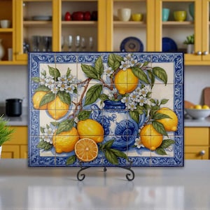 May include: A rectangular wall tile mural composed of twenty smaller tiles featuring a painted scene of bright yellow lemons, green leaves, and white blossoms arranged around a decorative blue and white ceramic pitcher on a cream background.
