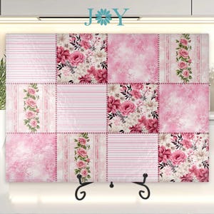 May include: A pink and white glass cutting board with a patchwork design featuring floral patterns. The board is on a stand and has a white background.